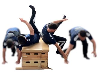 Ein Mann macht eine Parkourrolle auf dem Rücken über einen Kasten.